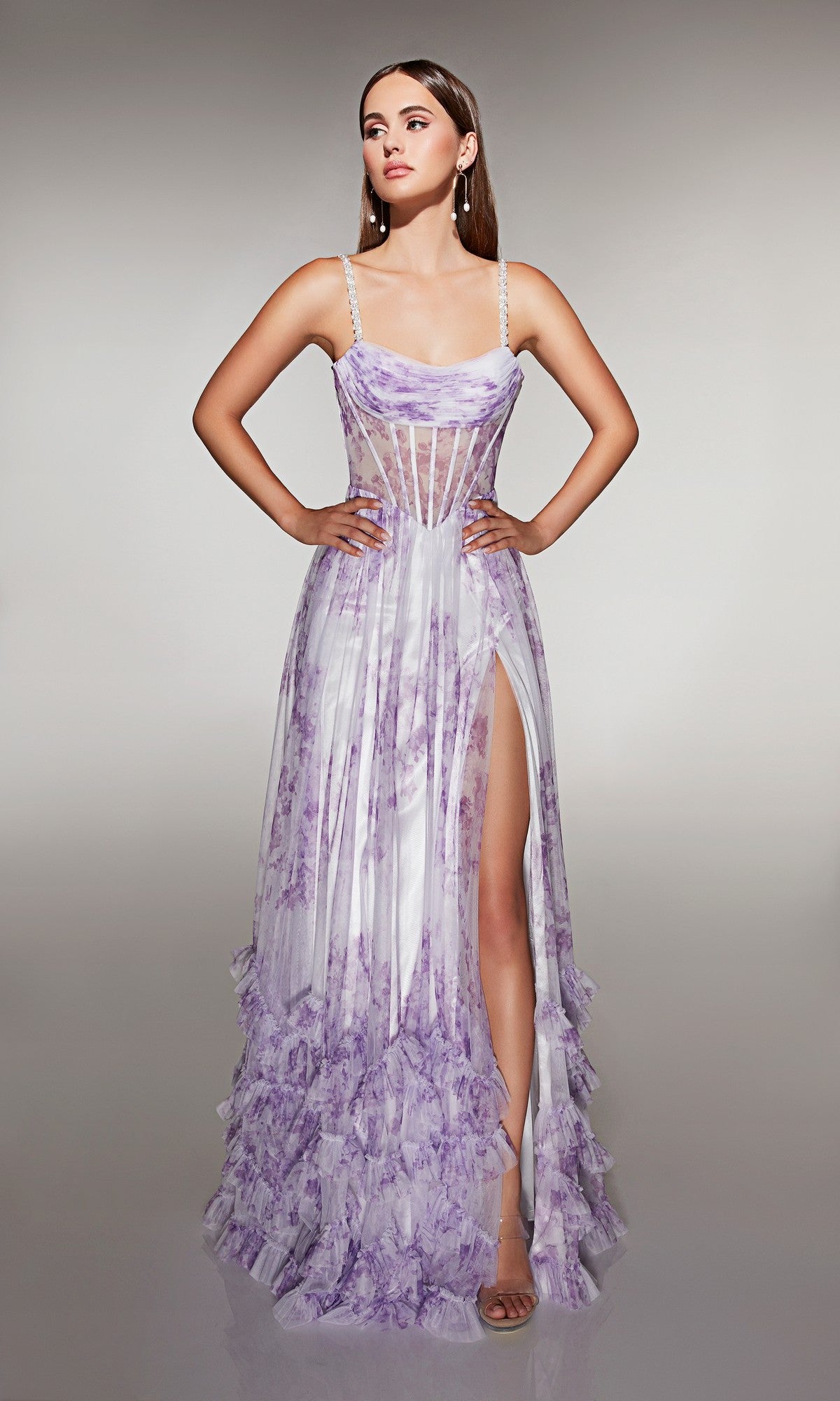 A woman stands with hands on hips against a plain background, wearing the Alyce 62202 long prom dress—a sleeveless, floor-length white and lavender gown featuring a sheer corset bodice and thigh-high slit.